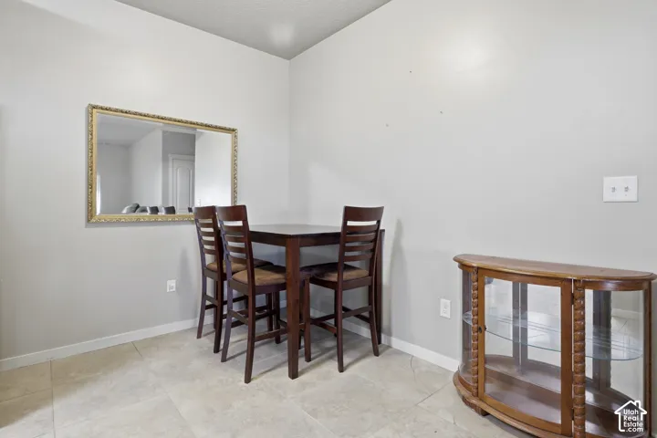 Neutral-toned interior space featuring light-colored stone-finish floor tiling and a wall-mounted rectangular mirror with a decorative gold-tone frame