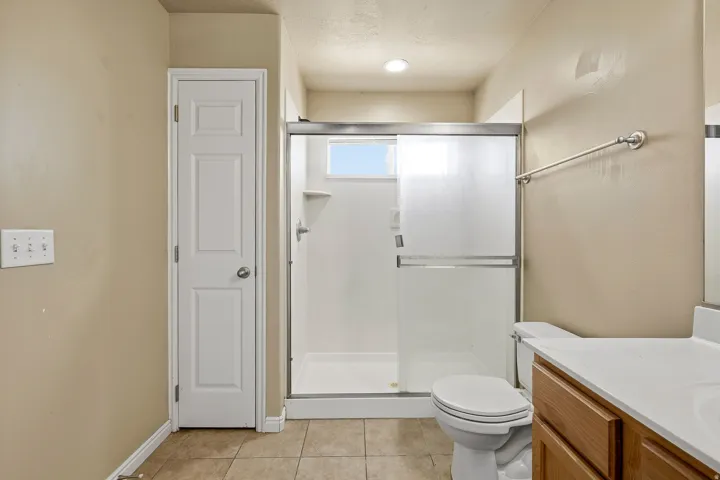 Bathroom featuring a white shower stall with sliding frosted glass doors and a small upper window