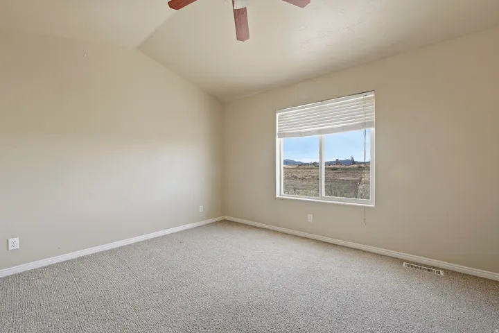 Spacious room featuring vaulted ceilings, light-colored carpeting, and a large window with horizontal blinds
