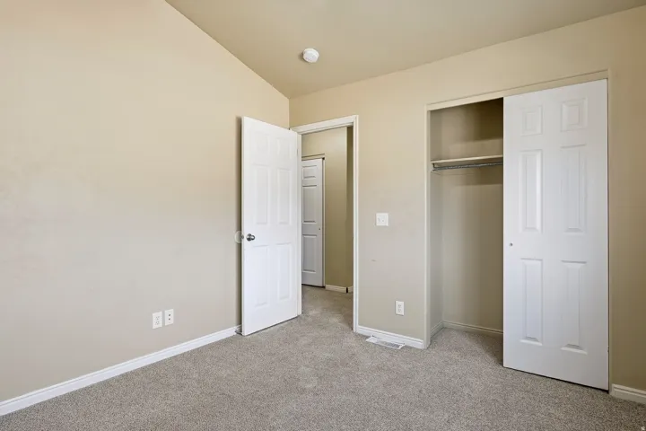 Carpeted interior room with neutral-toned walls, white trim, and a white six-panel door