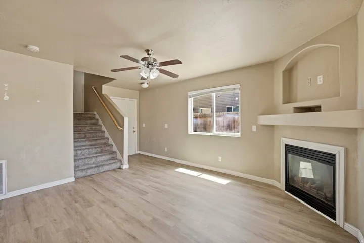 Living area with wood-finish flooring, a ceiling fan, and a fireplace featuring a built-in media niche