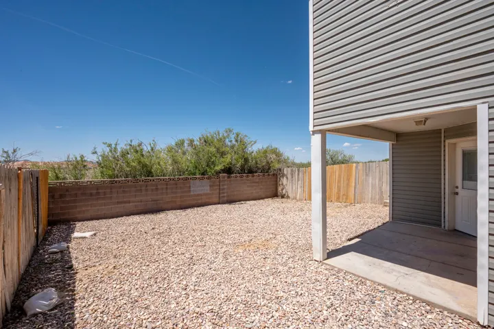 Ground-level patio with an overhead light fixture, overlooking a gravel-covered yard