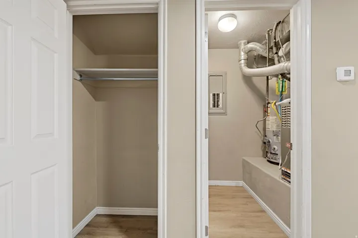 Interior closet with a clothes rod and upper shelf, featuring wood-finish flooring