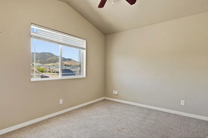 Vaulted ceiling room with neutral carpeting and a window featuring mountain scenery
