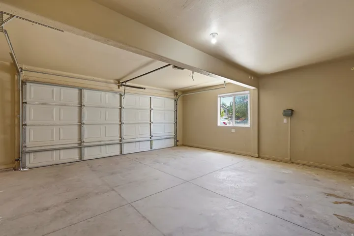 Two-car garage with concrete flooring, a single window, overhead lighting, and two sectional garage doors