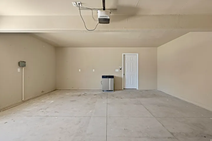 Spacious garage featuring a concrete floor, light-toned walls, and a white interior door