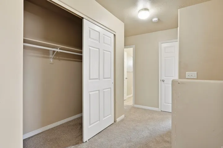 Carpeted hallway featuring a ceiling-mounted light fixture, neutral wall paint, and white trim