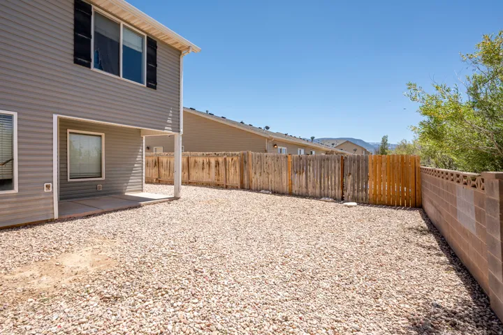 Expansive gravel backyard featuring a covered concrete patio