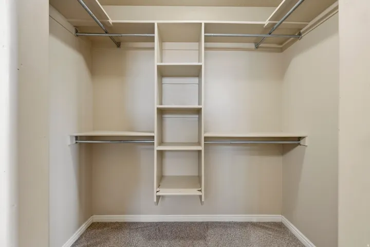Custom closet system featuring shelving units and multiple hanging rods