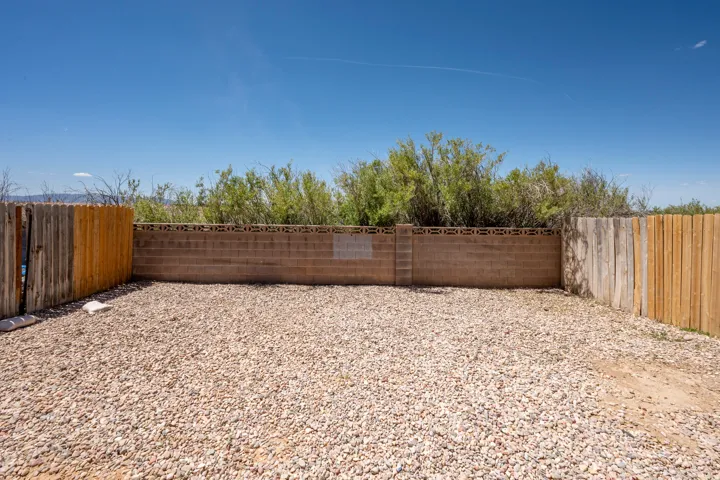 Gravel-covered outdoor space bordered by a combination of wood fencing and a concrete block wall with decorative top course
