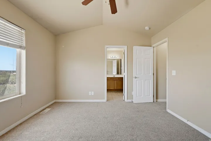 Carpeted room featuring a vaulted ceiling and a ceiling fan