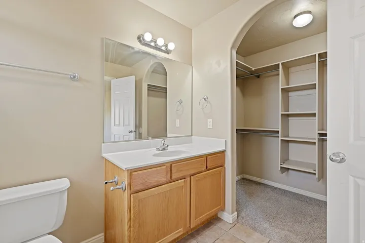 Bathroom vanity featuring a single basin sink, white countertop, and wood-finish cabinetry