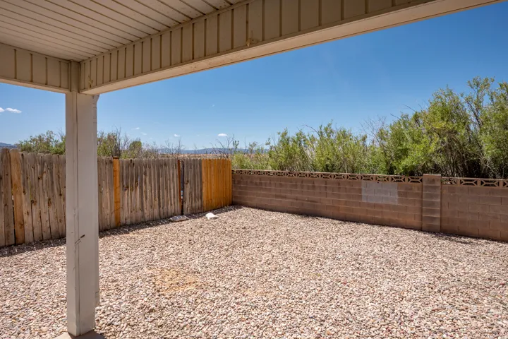 Covered patio area with a gravel ground cover and a combination wood and block perimeter fence