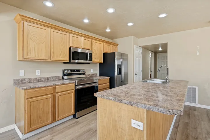 Kitchen featuring light wood-finish cabinetry, stainless steel appliances, and recessed lighting