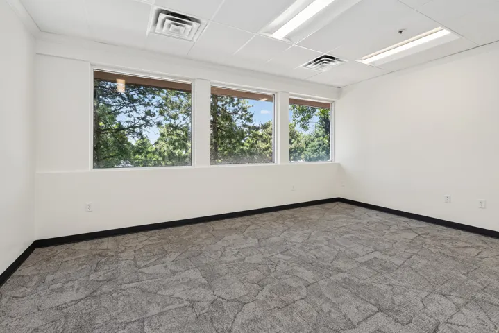 Interior space featuring three windows, neutral wall tones, drop ceiling, recessed lighting, and patterned carpet flooring