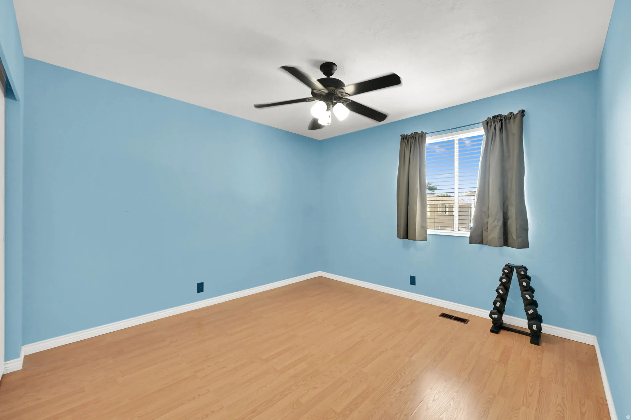 Wood-finish flooring, ceiling fan with integrated lighting, and a window with horizontal blinds