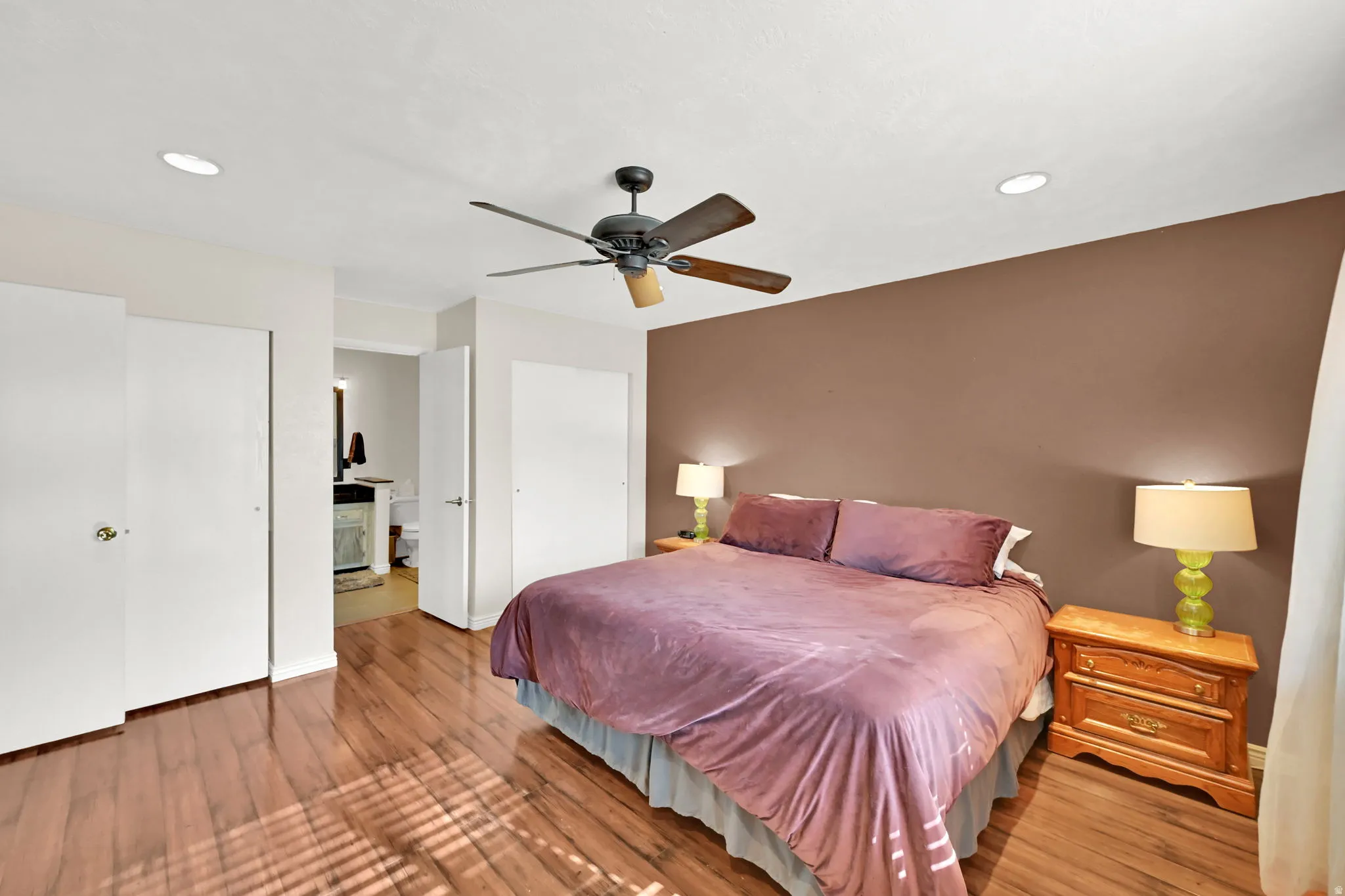 Wood-finish flooring with a ceiling fan, recessed lighting, and multiple closet doors