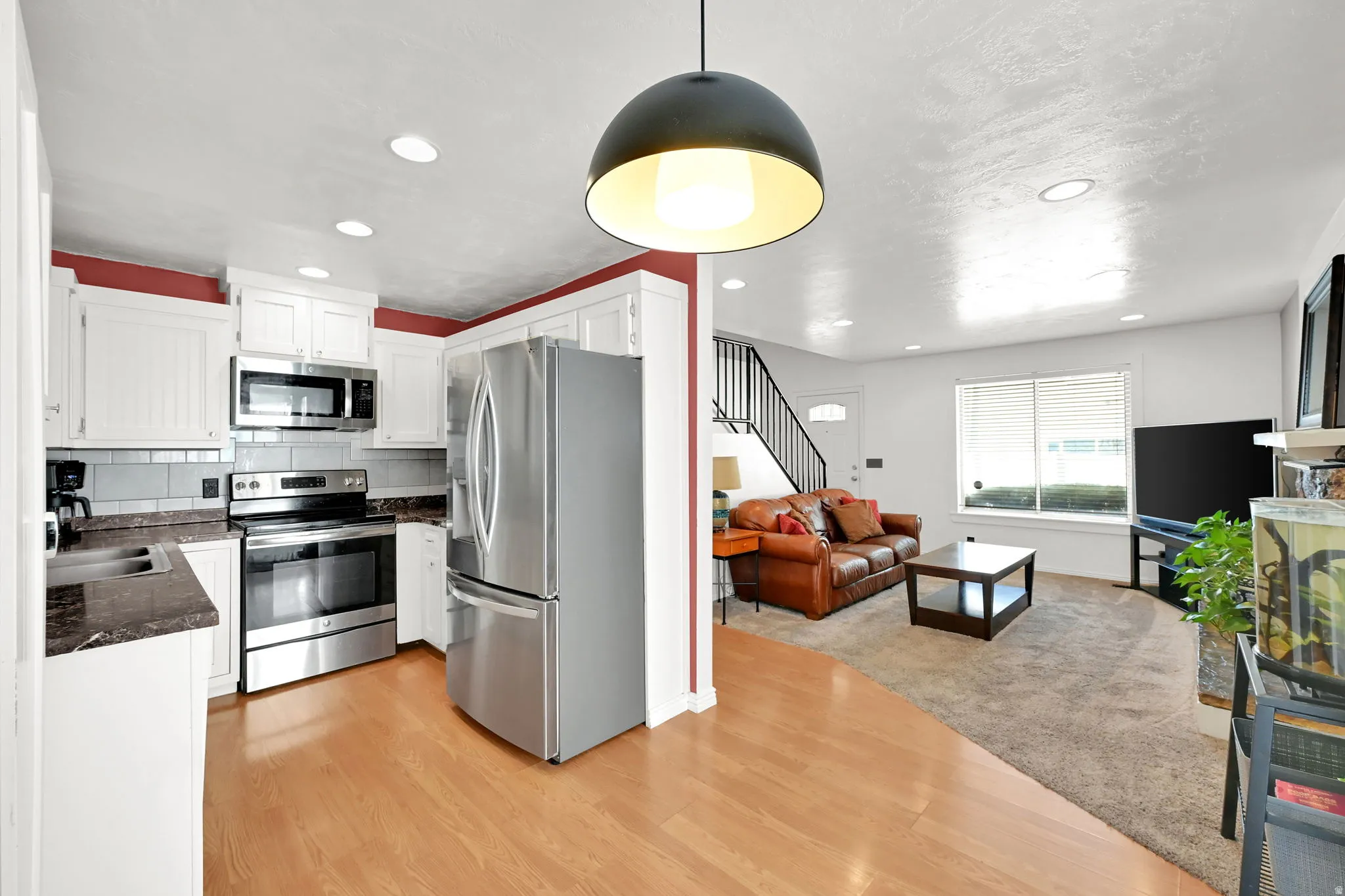Kitchen with white cabinetry, stainless steel appliances, and wood-finish flooring