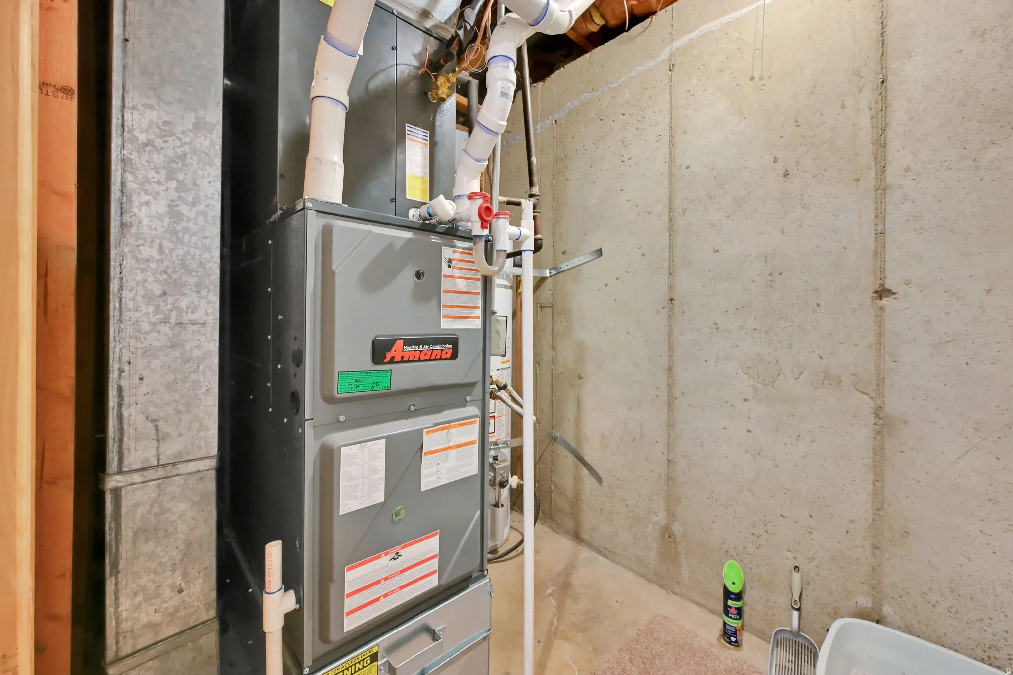 HVAC system with associated ductwork and piping, set against a concrete foundation wall