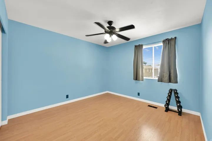Wood-finish flooring, ceiling fan with integrated lighting, and a window with horizontal blinds