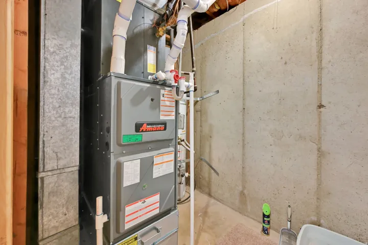 HVAC system with associated ductwork and piping, set against a concrete foundation wall
