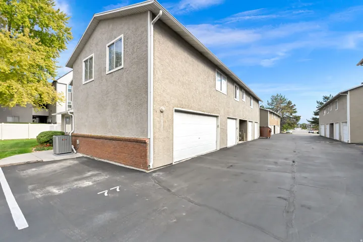 Stucco exterior with a brick foundation accent, multiple windows, and an integrated garage