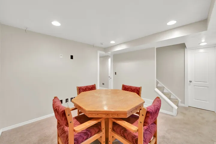 Recessed ceiling lighting, light neutral wall paint, white trim, and a carpeted staircase