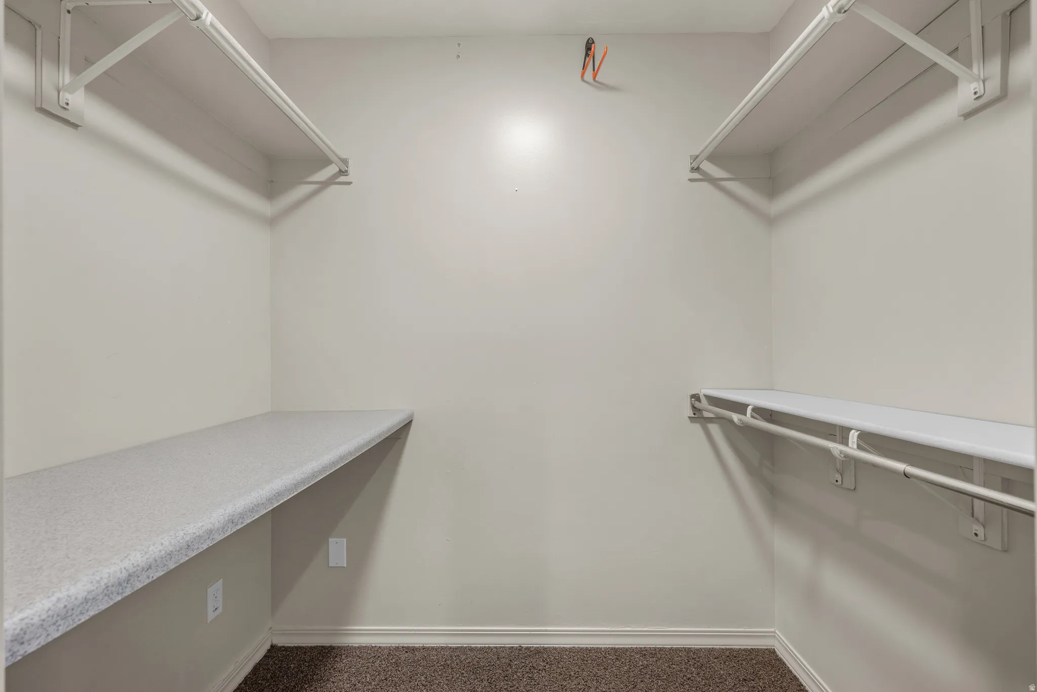 Spacious walk-in closet featuring dual built-in shelving units with granite-finish countertops, professional LED lighting systems, and polished metal hardware and rods for optimal organization and storage capacity
