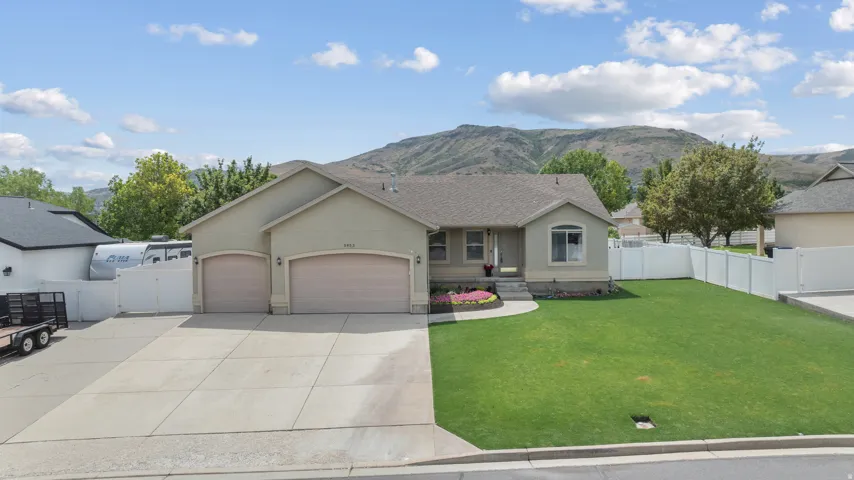 Welcoming single-story residence featuring a spacious two-car garage, concrete driveway, and manicured front lawn with mature landscaping