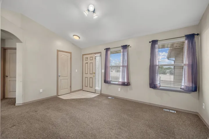 Carpeted living area with two windows, a tiled entry, and an archway