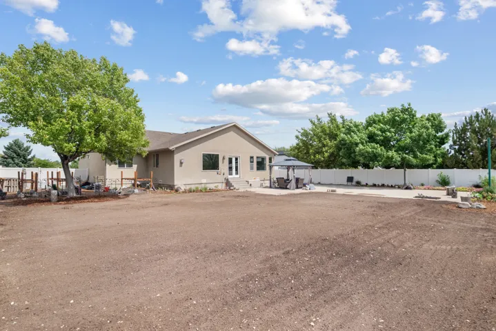 Expansive outdoor area featuring a stucco exterior, concrete patio, and a white privacy fence