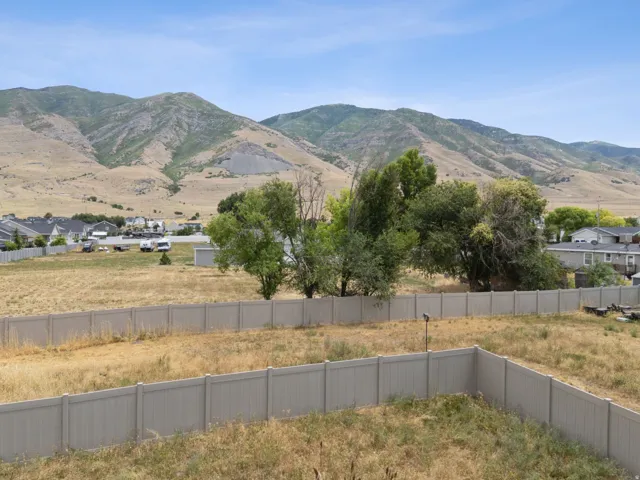 Expansive property featuring a vinyl privacy fence, mature trees, and a mountain backdrop