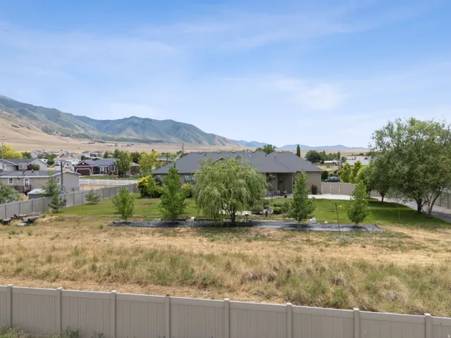 Expansive landscaped backyard with mature trees, a paved patio, and mountain scenery