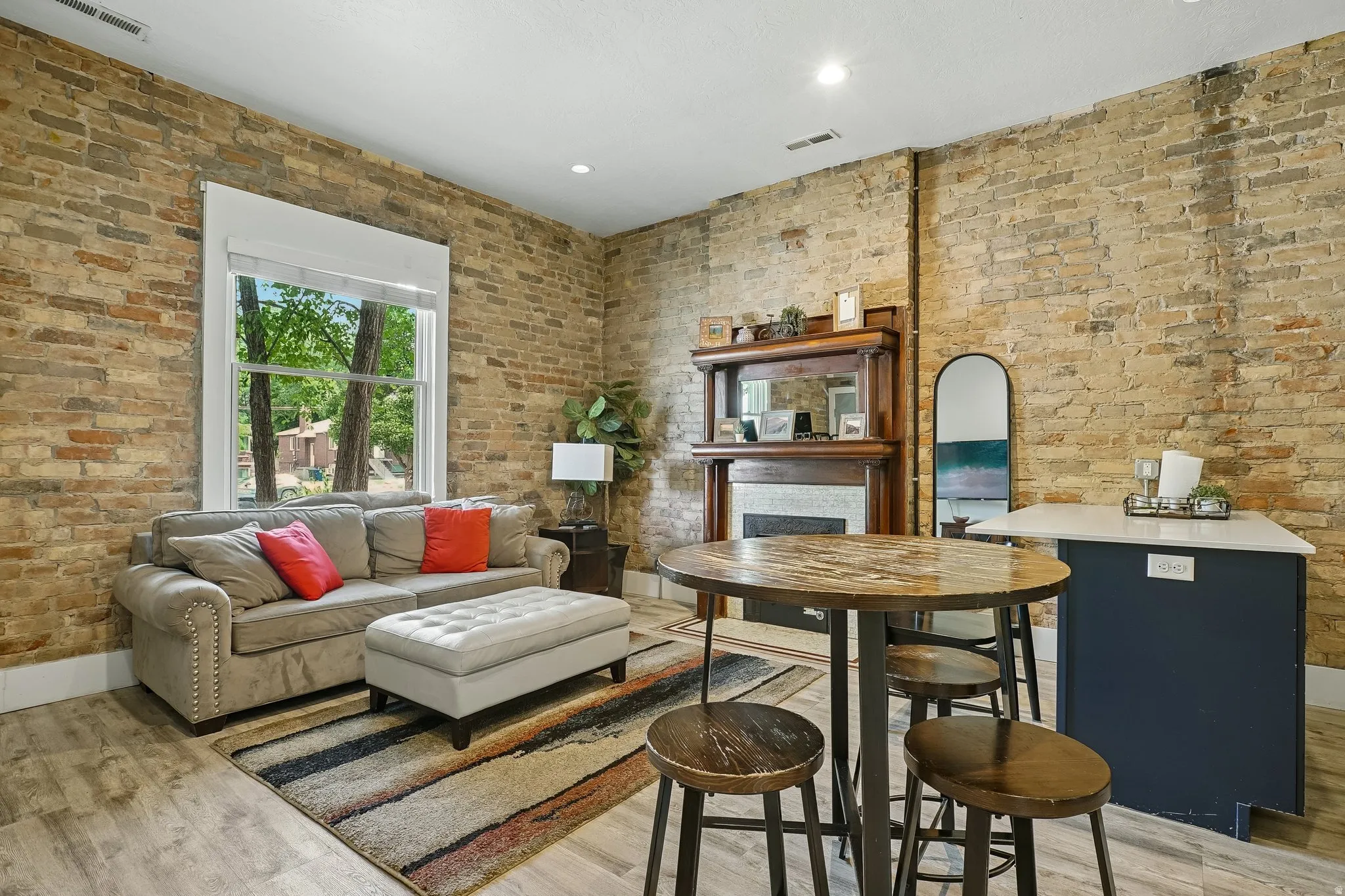 Exposed brick walls, wood-finish flooring, built-in fireplace, white trim window, and recessed lighting
