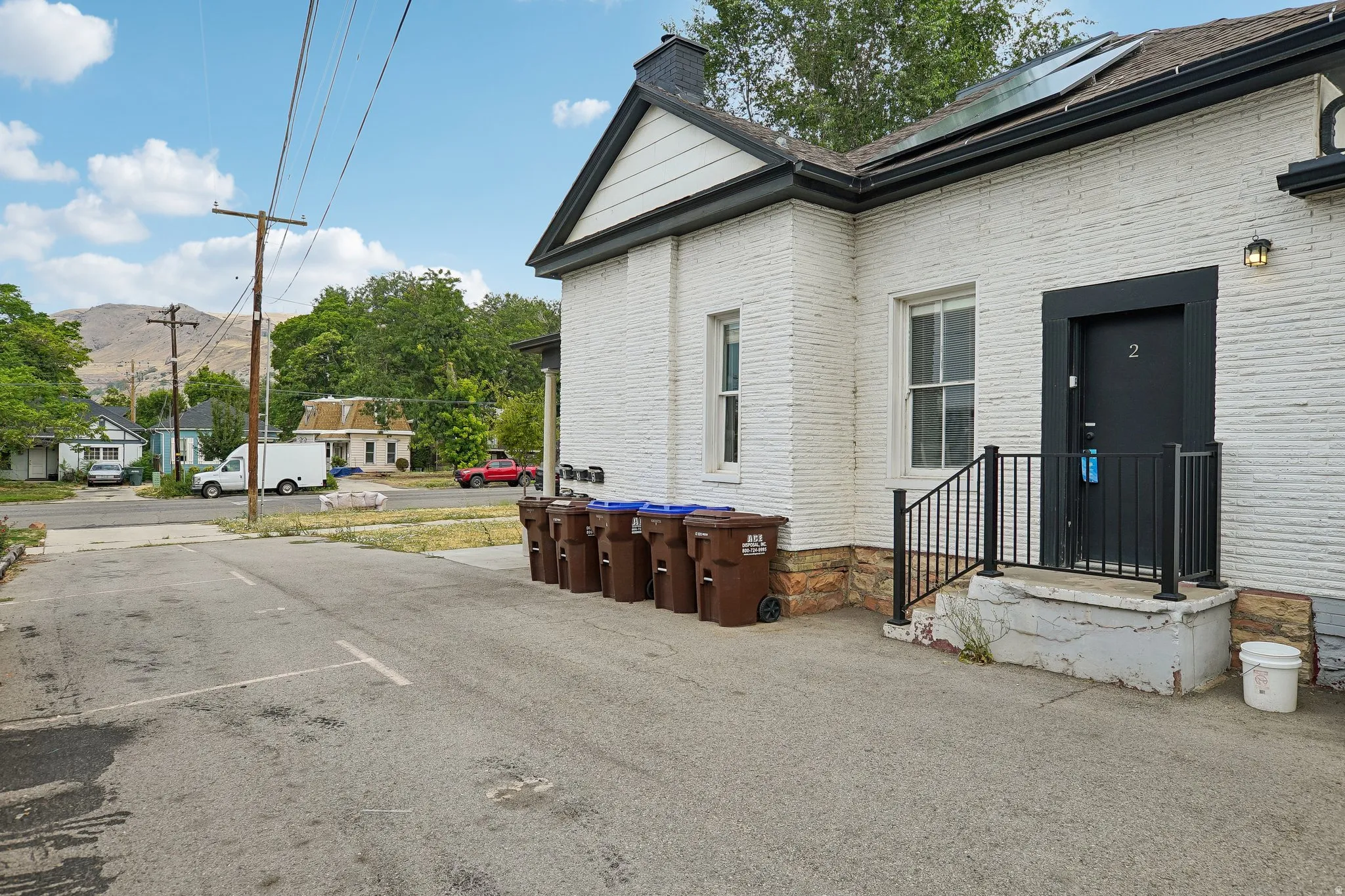 White painted brick exterior with dark trim and a prominent entrance door