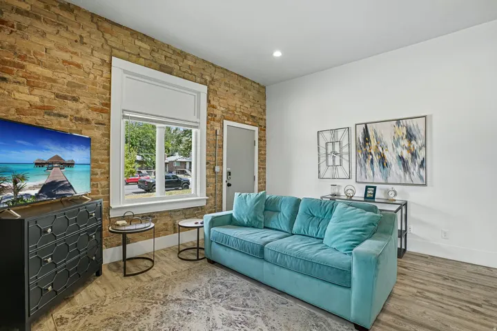 Bright recreational space featuring exposed brick accent wall, wood-finish flooring, and recessed lighting