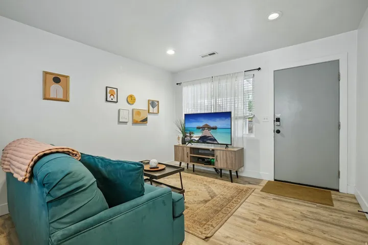 Recessed ceiling lighting, wood-finish flooring, and a modern gray entry door with integrated electronic lock