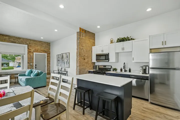 Open concept living space featuring exposed brick accents and wood-finish flooring