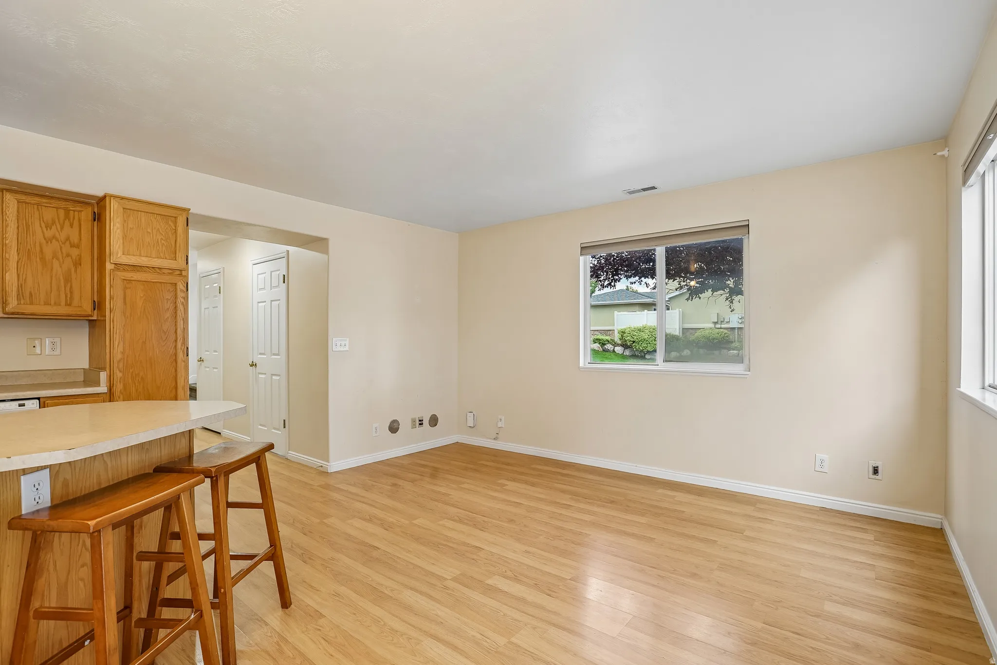 Open-concept living area with wood-finish flooring, a neutral color palette, and a large window
