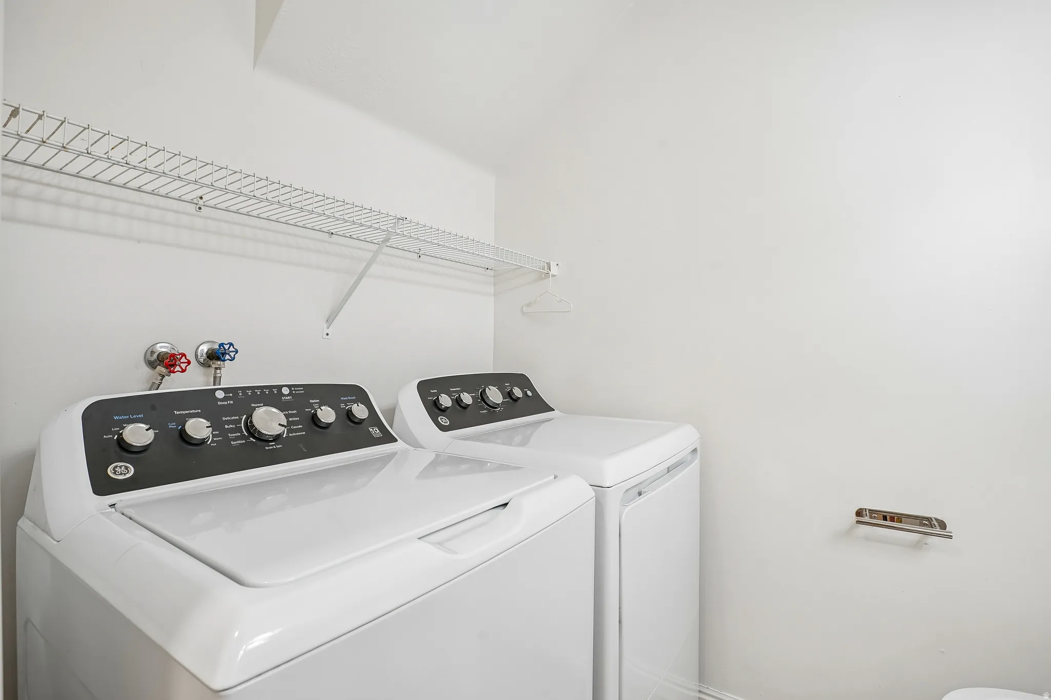Dedicated laundry area featuring a white wire shelf, top-load washer, and dryer
