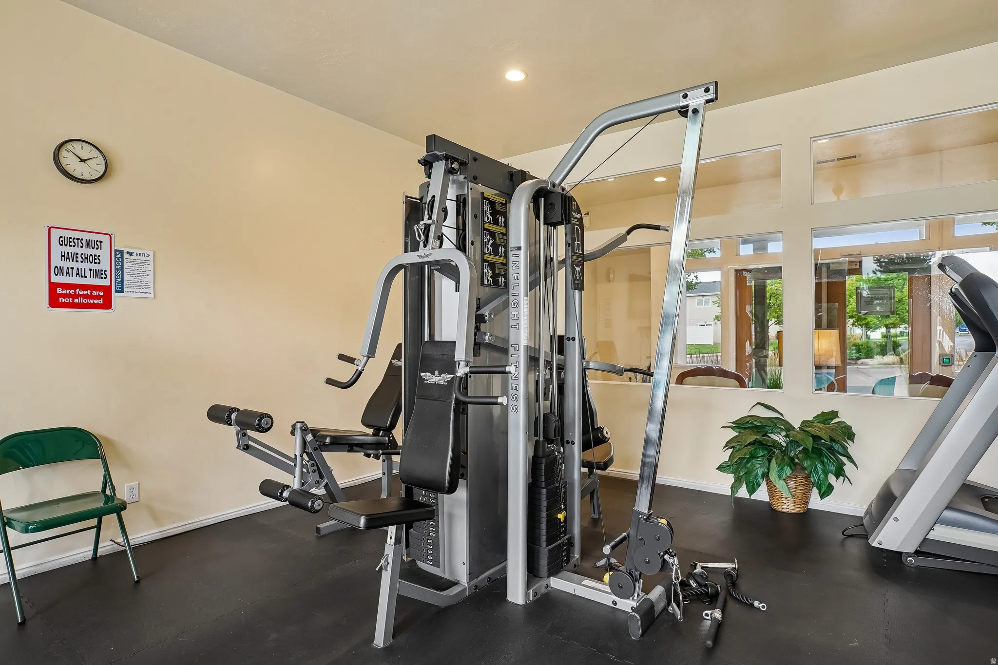 Dedicated fitness space featuring a multi-station weight machine, durable rubber flooring, ample natural light from multiple windows, and recessed ceiling lighting