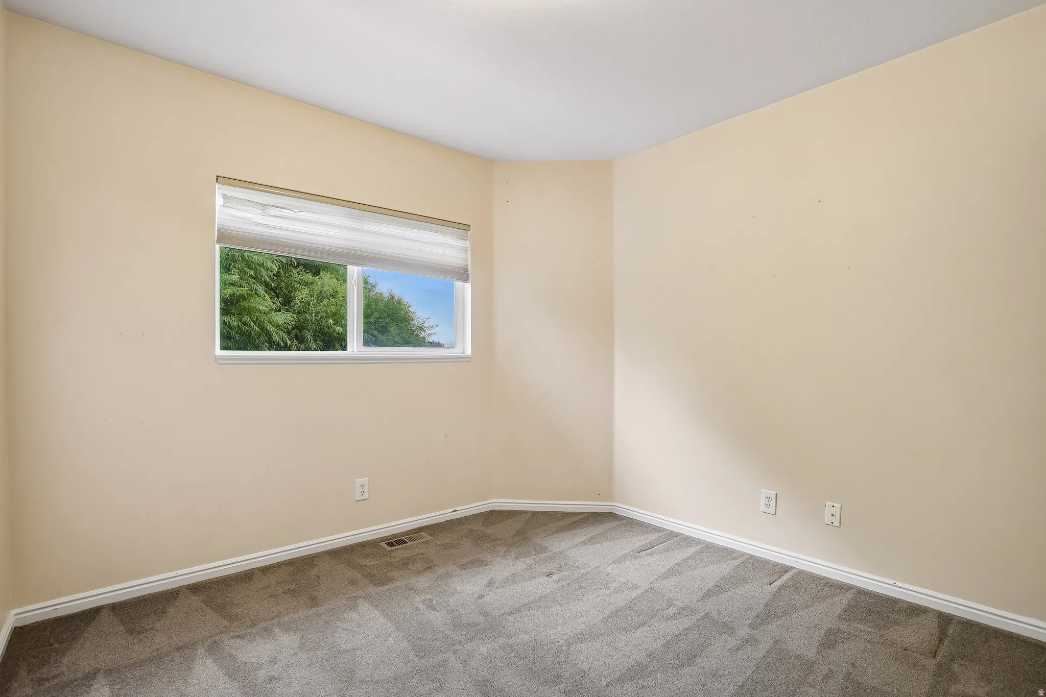 Carpeted interior room with neutral-toned walls and white trim
