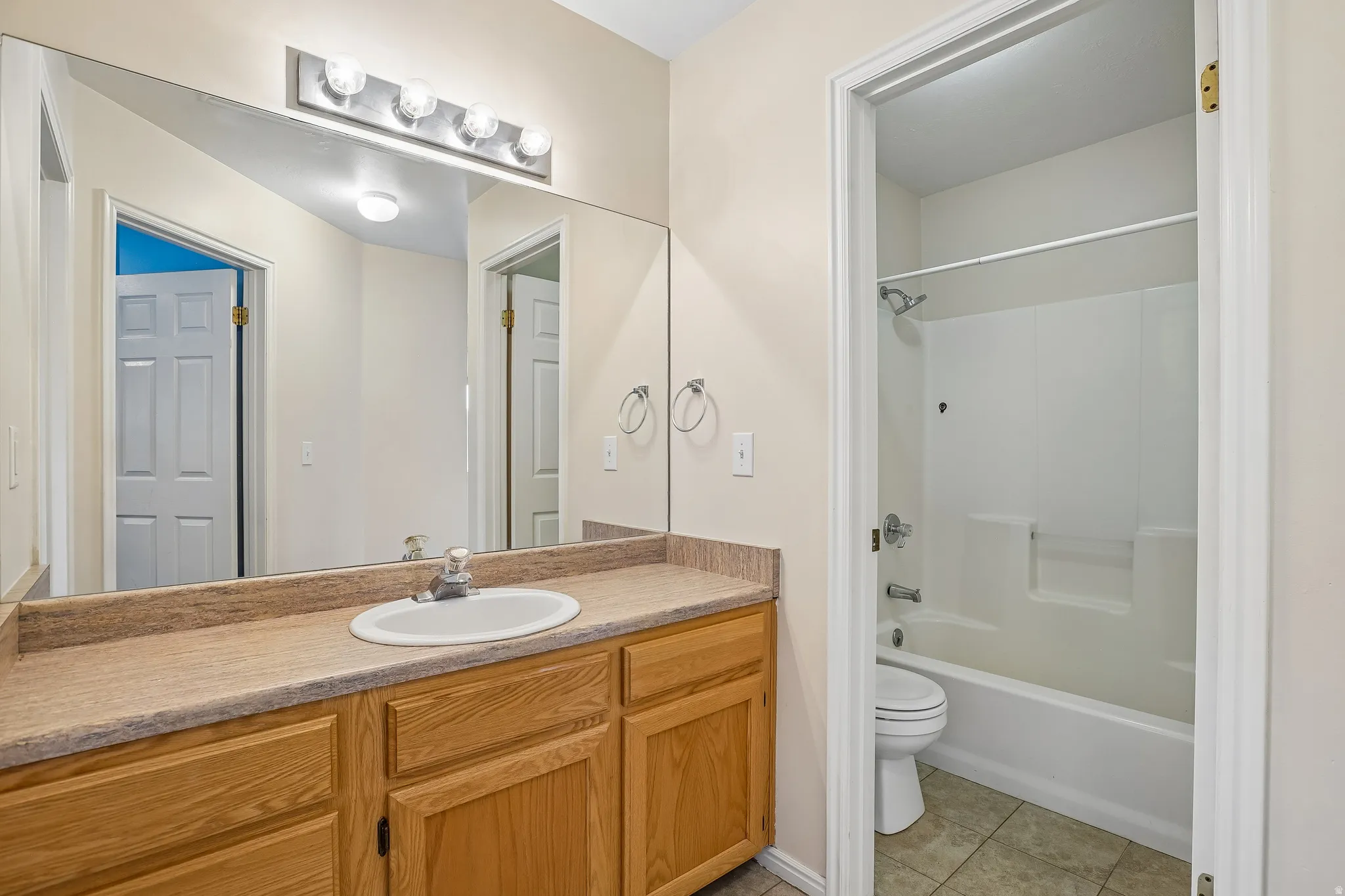 Bathroom vanity featuring a light wood-finish cabinet with multiple drawers and doors, a beige countertop, and an integrated white oval sink with a chrome faucet
