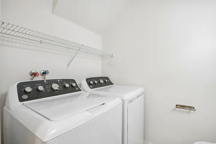 Dedicated laundry area featuring a white wire shelf, top-load washer, and dryer