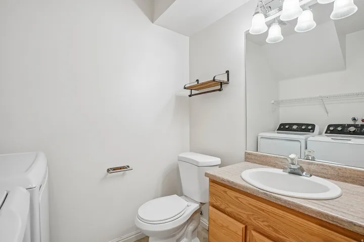 Powder room featuring a single vanity with wood-finish cabinetry, a large wall-mounted mirror, and a built-in toilet