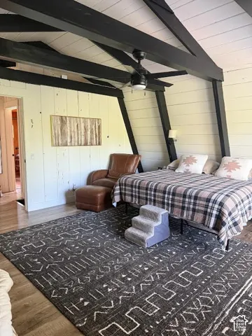 Vaulted ceiling with exposed black beams and a ceiling fan