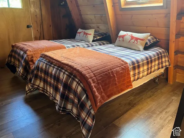 Sloped wood-paneled walls with two windows and wood-finish flooring