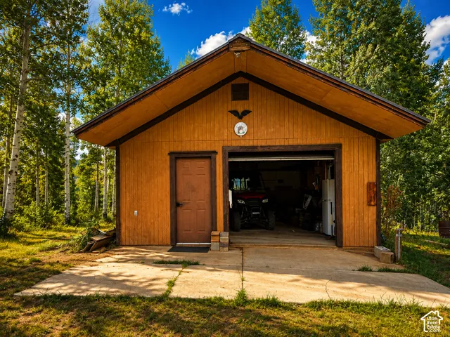 Detached garage with a single vehicle bay, concrete driveway, and natural wood siding