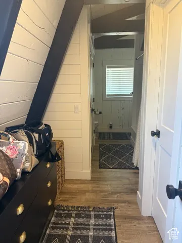 Hallway featuring wood-finish flooring, shiplap wall detailing, and neutral paint finishes