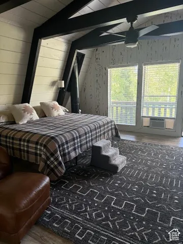 Vaulted ceiling with exposed black beams and light wood-finish paneling